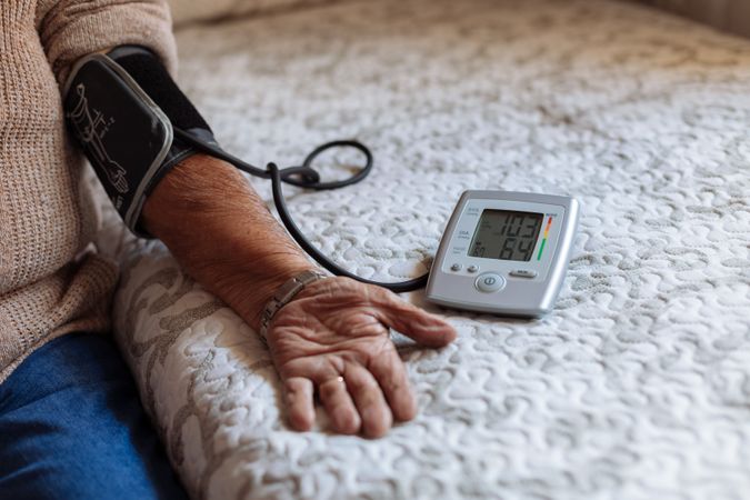 older man checking his arterial pressure with machine