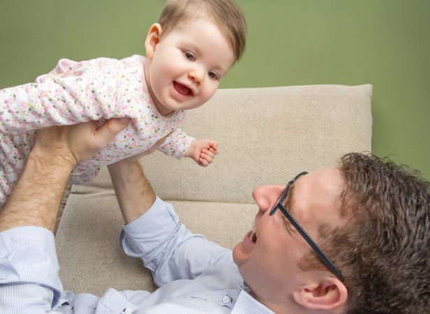 Father lifting baby daughter above his chest