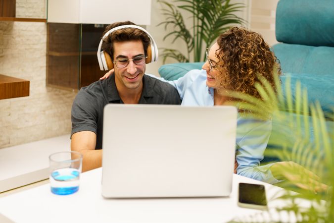 Happy couple using laptop at home in living room