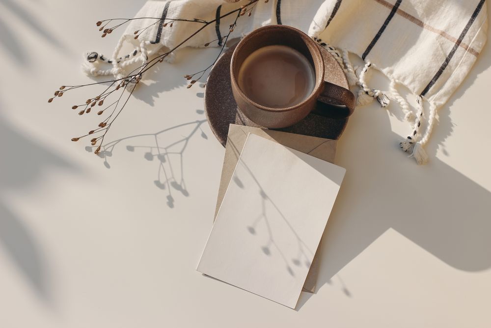 Cup of coffee and checkered plaid on table with mockup card