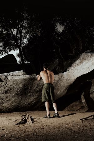 Man practicing rock climbing among large rocks in a forest
