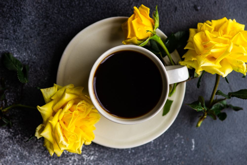 Top view of cup of coffee and yellow roses