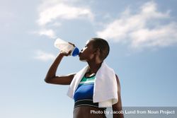 Fit woman drinking water against sky 0gaXM4