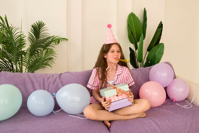 Young girl celebrating her birthday at home, holding presents.