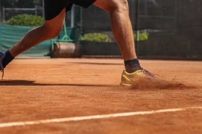 Man in sportswear playing tennis on a dirt tennis court
