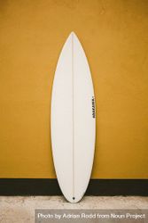 Surfboard against a yellow wall 4dOON5