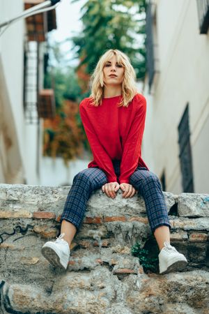 Stern blond woman sitting on stone wall