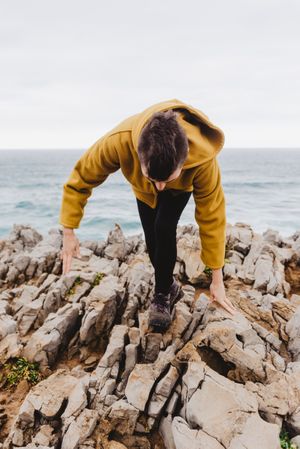 Woman in yellow hoodie on stony shore