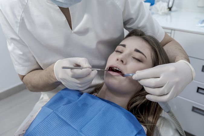 Dentist examining teenage girl's teeth in clinic