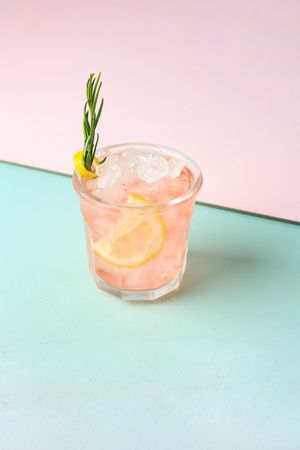 Iced pink drink with rosemary garnish