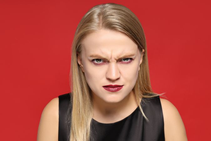 A young woman in a zombie costume, on the occasion of the Halloween holiday, on a red background.