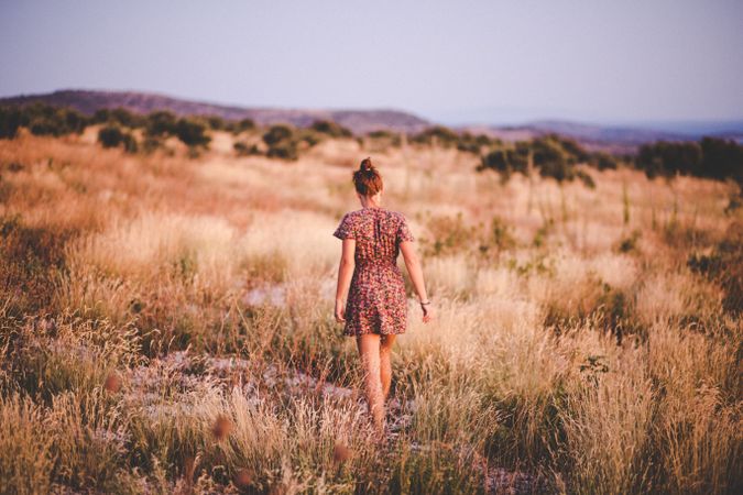 Woman in short dress standing on brown grass field