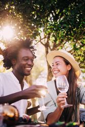 A man and woman smiling drinking wine outside