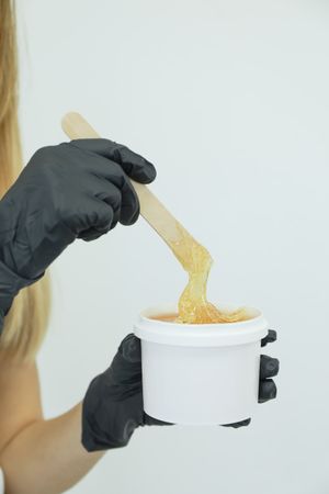 Woman holding liquid yellow paste for sugaring