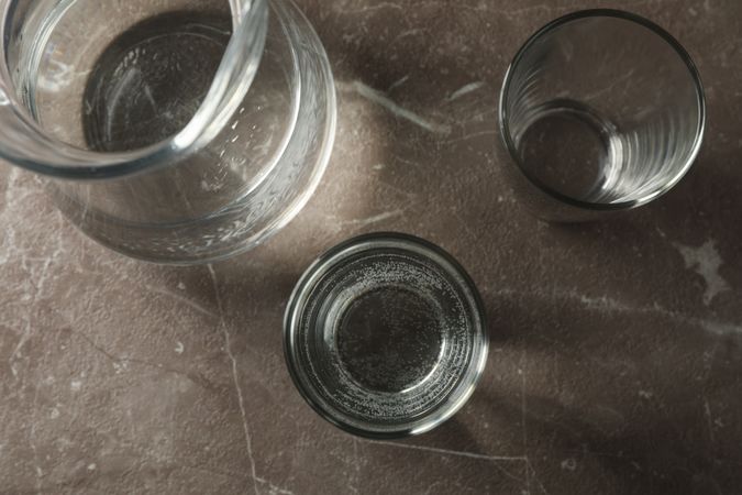 Top view of glasses of water and pitcher on grey marble table