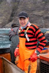 Portrait of a young fisherman in apron working holding lobsters