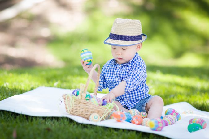 Biracial Baby Boy Outside Wearing Rabbit Ears Playing with Easter Eggs