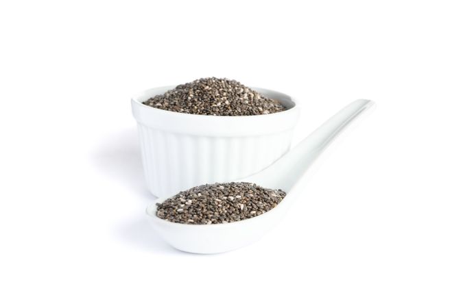 Chia seeds in porcelain spoon and sauce boat isolated on plain background