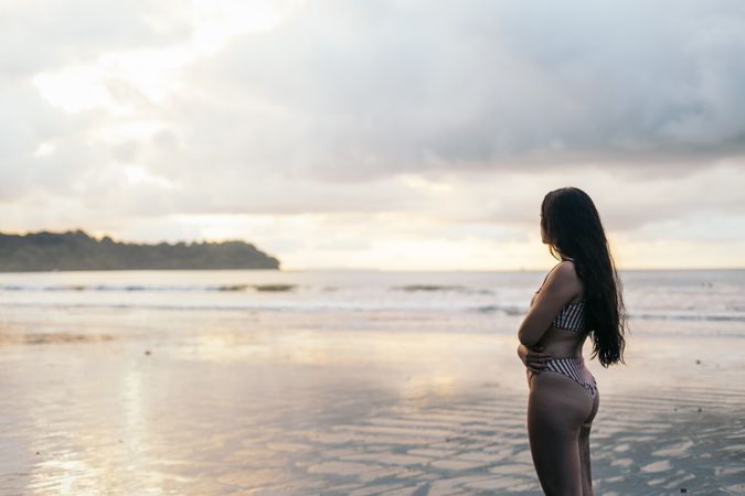 Young woman watching sunset standing on the beach