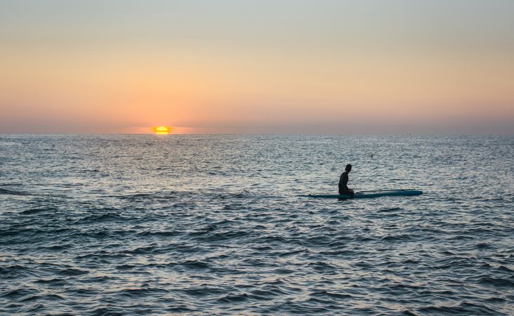 Man practicing paddle surfing with neoprene in a sunrise