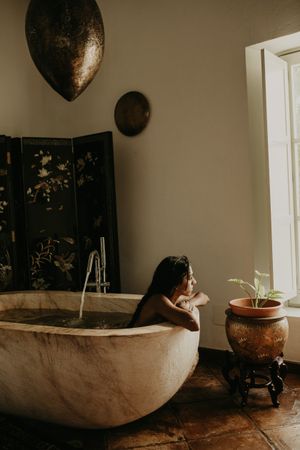 Melancholic Woman sitting and washing in bath
