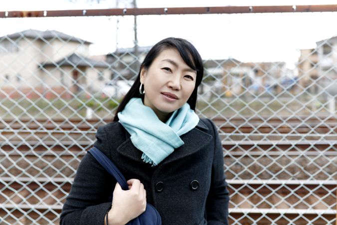 Portrait of woman in blue scarf standing beside fence outdoor