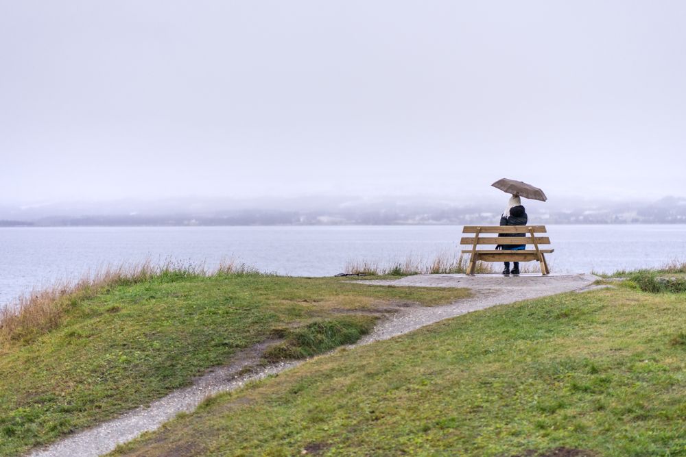 Woman sitting under umbrella on coast