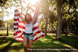 Smiling young woman with USA flag at park 5rnn25