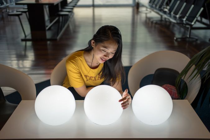 Asian woman examining round lamps on table