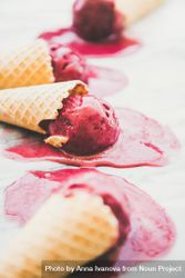 Cones of dark berry ice cream melting on marble slab, vertical composition, side view 4d3VQ5
