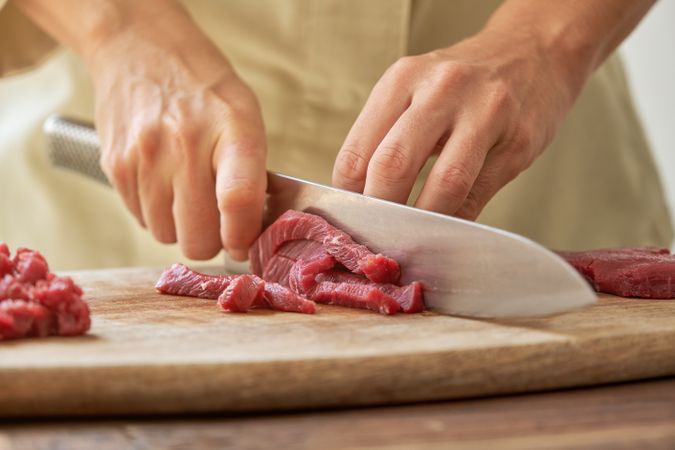 Unrecognizable woman cutting meat on board