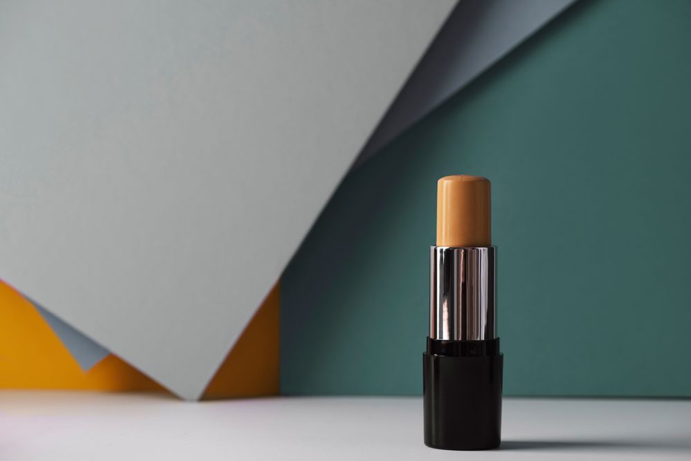 Concealer stick on modern background with geometric shapes.