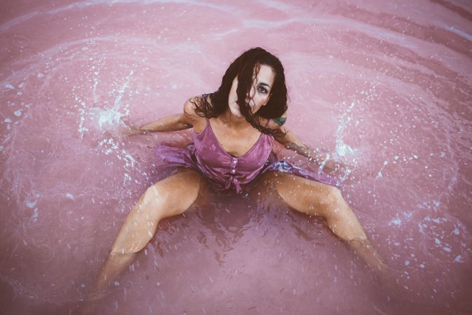 Woman in wet dress sitting in water
