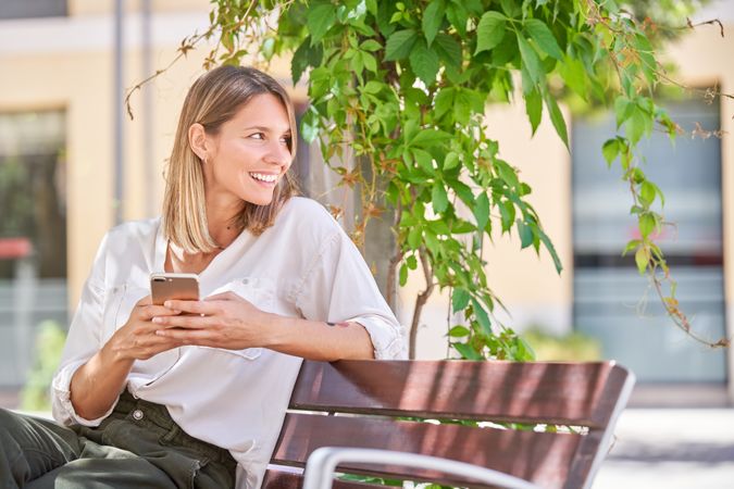 Happy female using smartphone on street