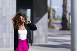 Female in bright pink trousers enjoying the sun while strolling outside