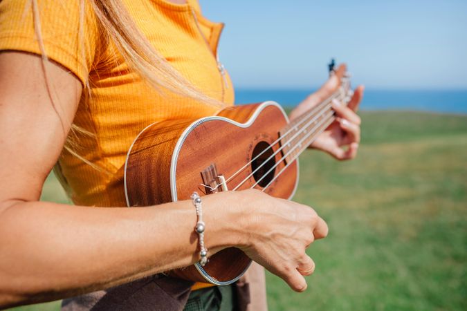 Close up of woman’s torso playing ukulele