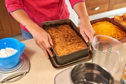 Crop person with baked biscuit cake in kitchen