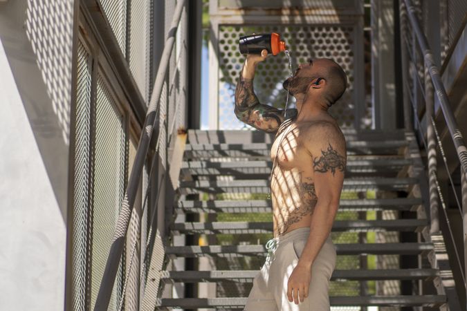 Shirtless man drinking during training