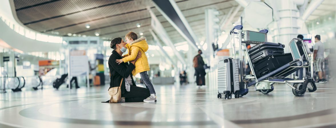 Wide angle view of a woman kissing her son at airport terminal