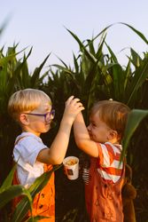 Happy kids giving high five in lush agricultural field at sunset