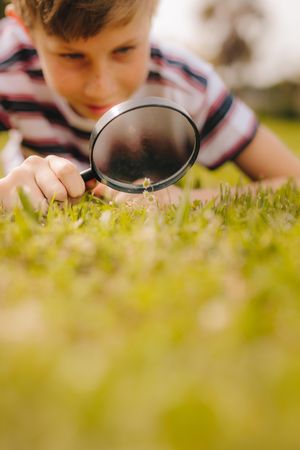 Kid playing with magnifying glass outdoors