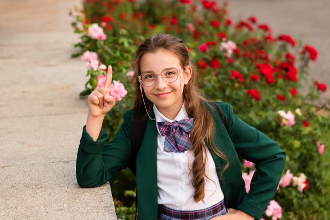 Young girl in school uniform raising  finger