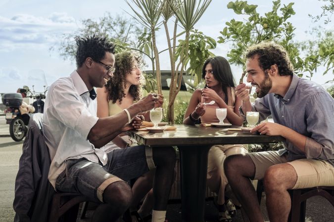 Group of diverse friends eating dessert at an outdoor cafe in Italy
