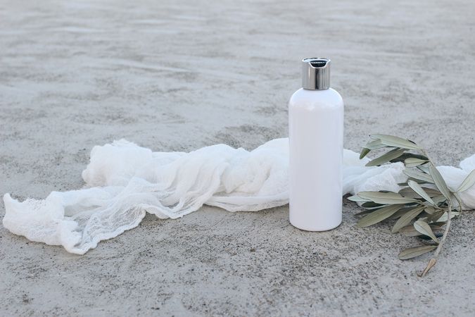 Cosmetic plastic bottle mockup with green olive tree branch and muslin cloth