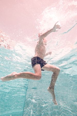 Underwater shot of anonymous boy swimming in pool