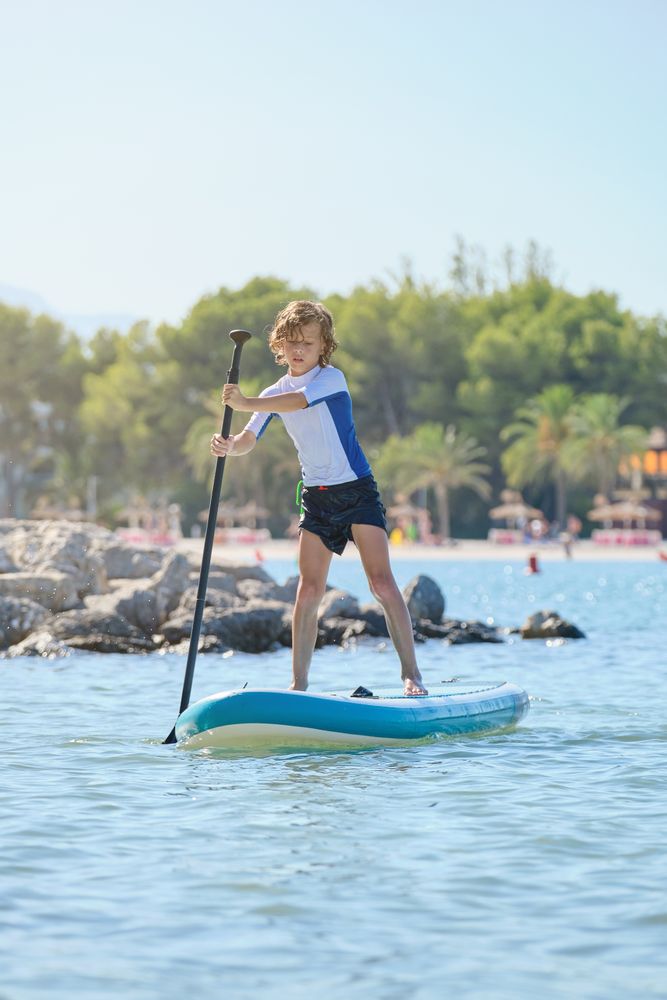 Concentrated kid balancing on paddleboard in sea