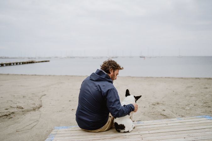 Man and dog resting on beach together