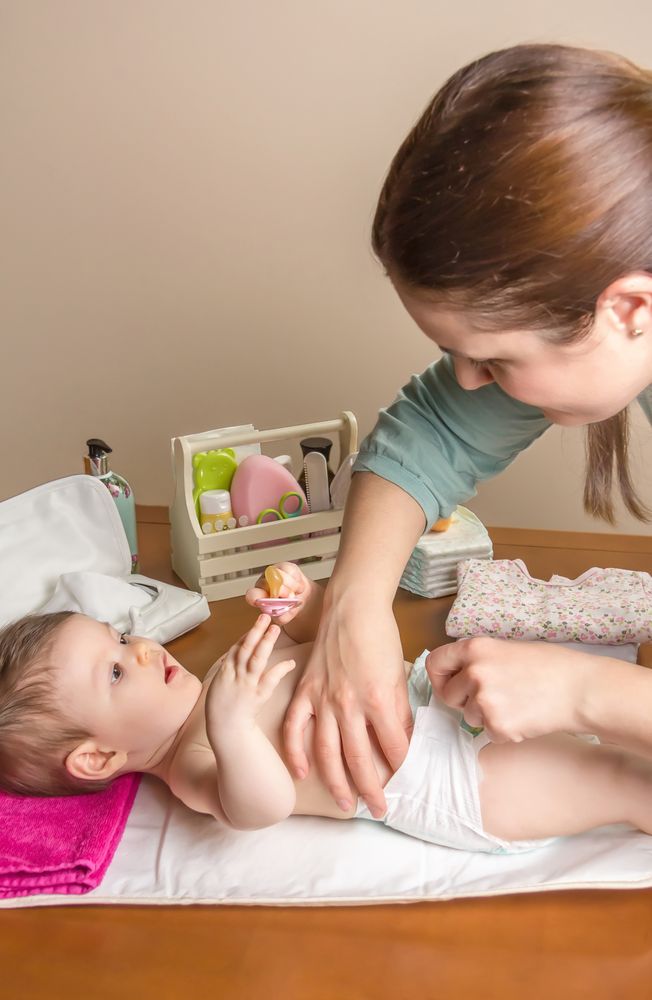 Mother changing diaper of baby, vertical