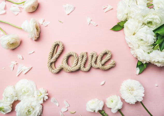 “Love” written in jute against pink background surrounded with flowers
