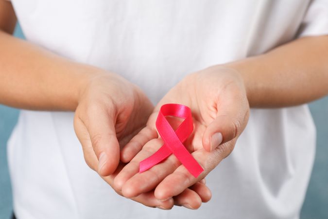 Person in t-shirt hold awareness ribbon against blue background